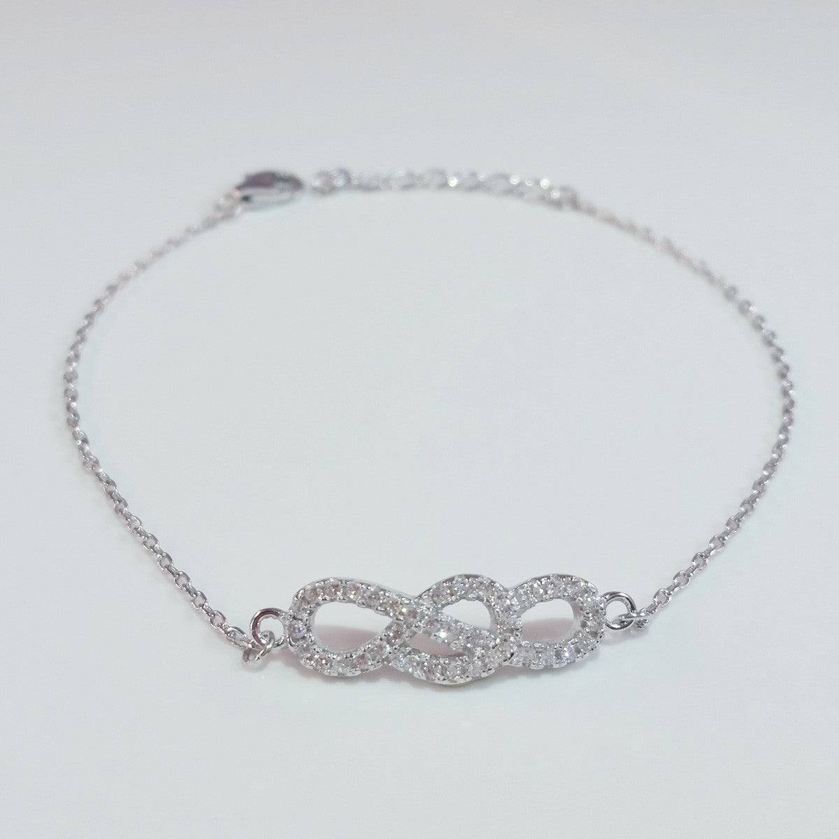 925 STERLING SILVER BRACELET WITH INFINITY CHARM PAVED WITH SPARKLING CZ CRYSTALS.