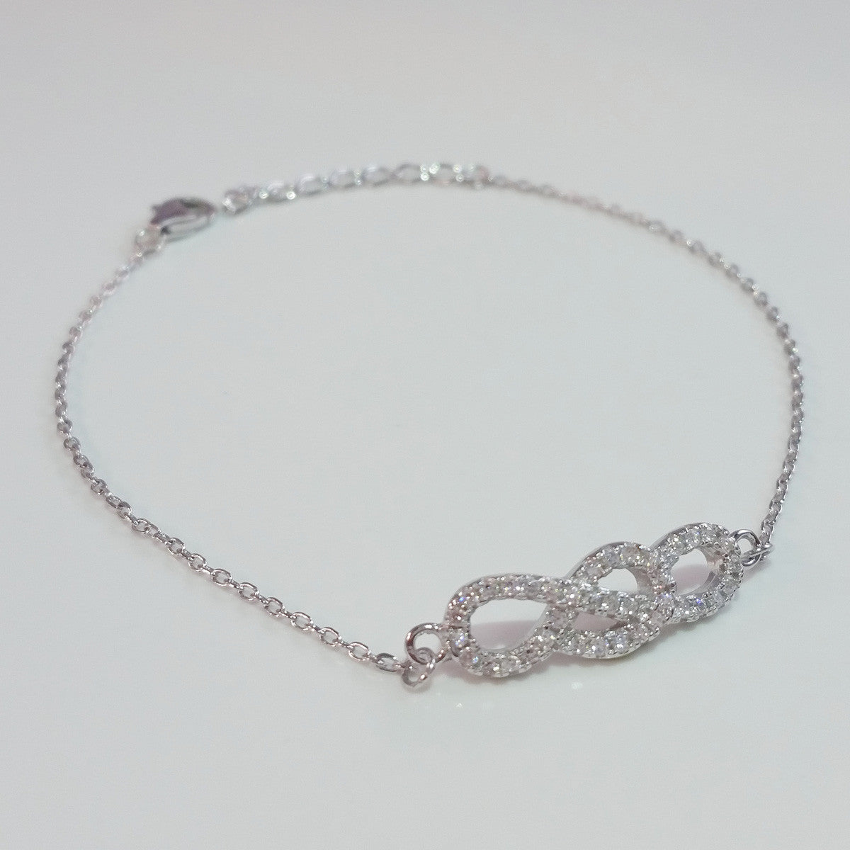 925 STERLING SILVER BRACELET WITH INFINITY CHARM PAVED WITH SPARKLING CZ CRYSTALS.