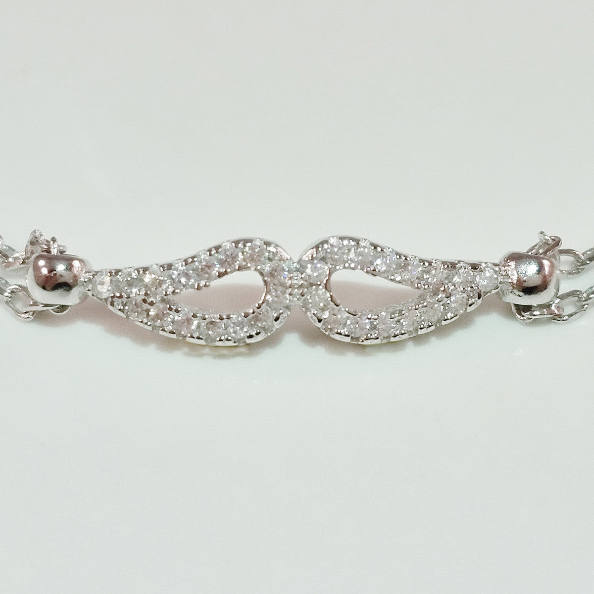 925 STERLING SILVER BRACELET WITH ANGEL WINGS CHARM PAVED WITH SPARKLING CZ CRYSTALS.