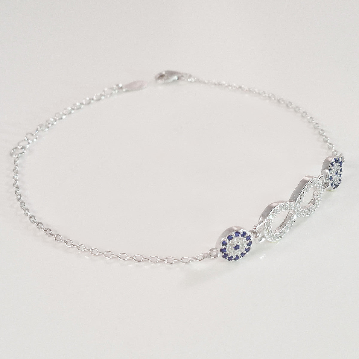 925 STERLING SILVER BRACELET WITH ETERNITY SYMBOL AND DOUBLE EVIL EYE CHARM PAVED WITH SPARKLING CZ CRYSTALS.