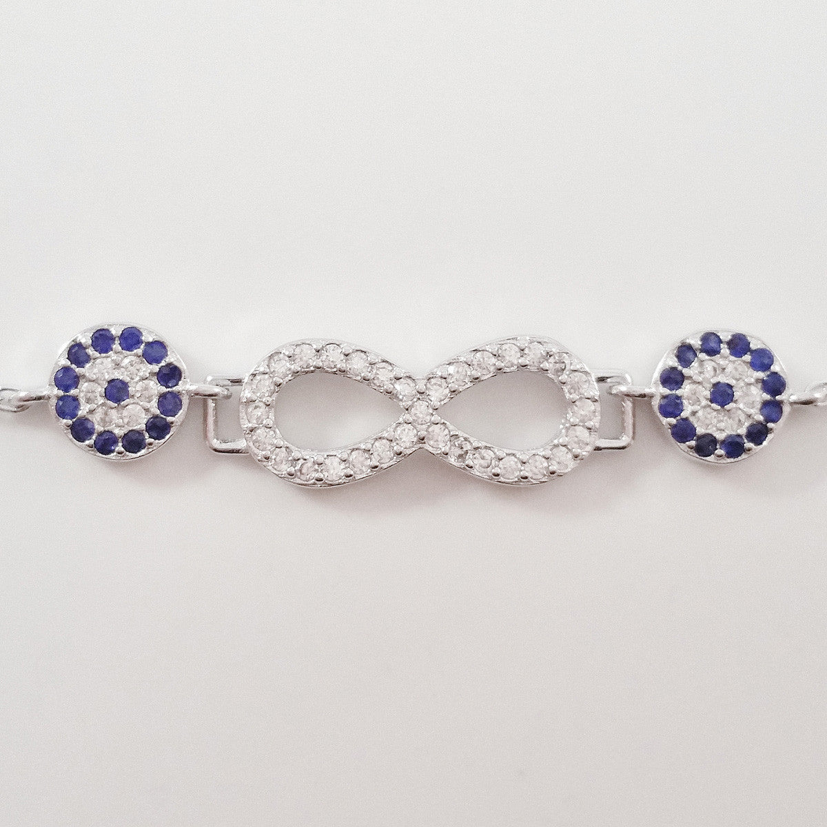 925 STERLING SILVER BRACELET WITH ETERNITY SYMBOL AND DOUBLE EVIL EYE CHARM PAVED WITH SPARKLING CZ CRYSTALS.